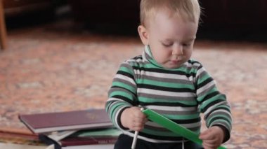 Çekici bir oğlu evde plastik cetvelle çalıyor. Elinde bir kalem tutar. Çocuk bir yıl önce alınmış.