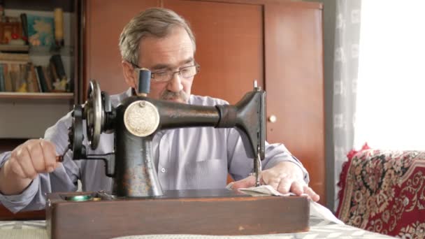 성인 남자는 콧수염와 오래 된 손으로 수 놓은 기계에 sews. 안경은 옷과 흰색 옷에 꿰 매. — 비디오