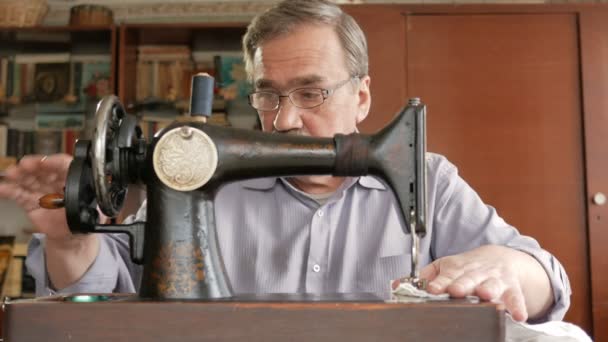 一个留着小胡子的成年男子缝制老手工缝制的机器上。眼镜是穿着和白布缝上. — 图库视频影像