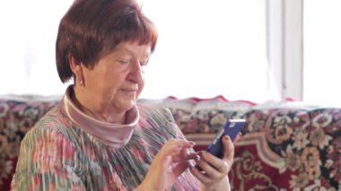 Yaşlı bir kadın cep telefonu kısa mesaj yazıyor. O dikkatle ekranda presler ve metni telaffuz.