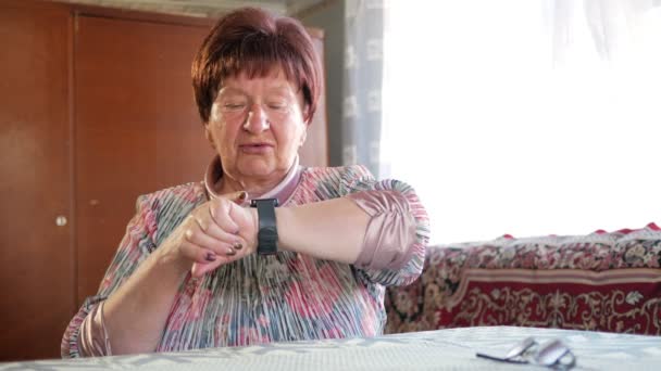 Een oudere vrouw controleert de berichten op een slimme horloge. Ze leest herinneringen en spreekt de uitdrukking voor een zoekopdracht. Na het lezen van het resultaat — Stockvideo