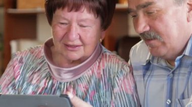 Yaşlı bir çift ile onların torun tablet bağlama video tarafından iletişim kurar. Bir erkek ve bir kadın yakınlarına konuşuyorsun.