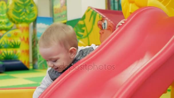 Cute kid jest stojący w pobliżu czerwony slajdów w parku rozrywki — Wideo stockowe