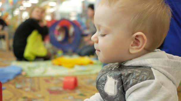 Милий блондинка два роки грає в дитячому освітньому центрі. Хлопчик їсть міцну мотузку — стокове відео
