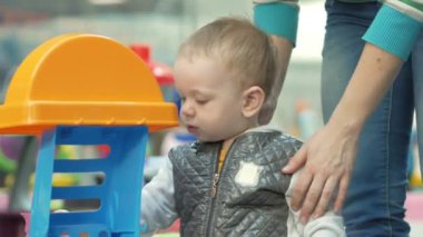 Sevimli sarışın bebek alışveriş merkezinde oyuncaklarla oynuyor. Ne zaman alışveriş çocuk bırakmak çocuk alanı