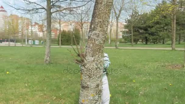 Toddler pojke leker i parken med mamma under våren. Han går och ser sig omkring. Rörlig kamera — Stockvideo