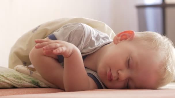 Çocuk kanepede yatıyor ve uyanmaya başlar. O gözlerini açar ve onları elleriyle losyonları — Stok video