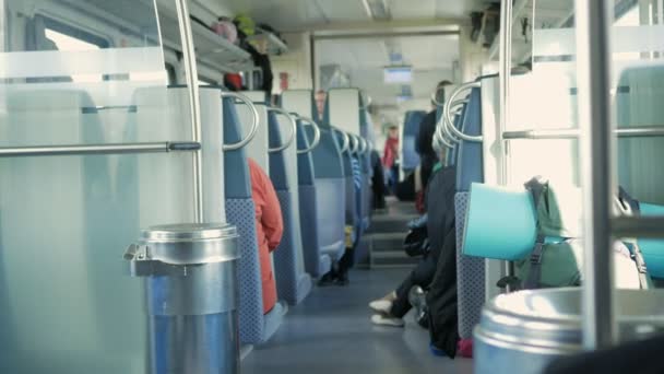 Bewegende trein binnen. Mensen zitten op hun plaatsen, dingen zijn verspreid op de vloer en planken — Stockvideo