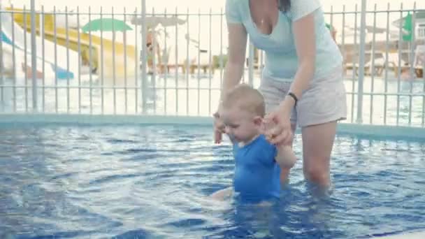 Mamma guida una mano di bambine in una piscina per bambini per strada. Ragazzo biondo senza peli meno di due anni — Video Stock