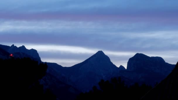 La noche cae en un valle montañoso. Las nubes cambian de color de multicolor a oscuro. Plazo de entrega — Vídeo de stock