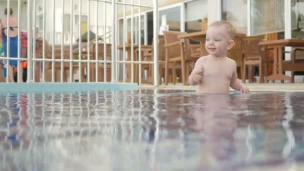 Dítě jde kolem dětský bazén na ulici. On má vodu a hraje s kapkami. — Stock video