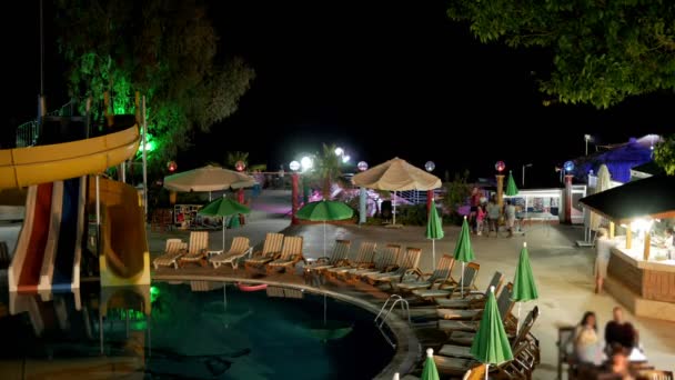 Recreation area with a hotel pool at night. People quickly go to the bar and talk to each other. TimeLapse — Stock Video