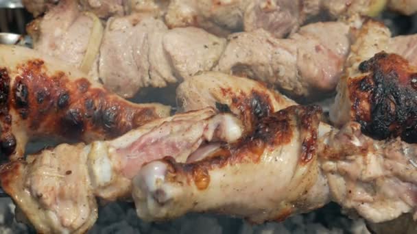 Preparación de carne sobre carbón vegetal en la calle. El pollo y la carne de cerdo están atados a alfileres metálicos. Cámara móvil — Vídeo de stock