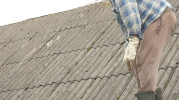 Un vieil homme répare lui-même le toit. Vieille maison en bois en ardoise — Video