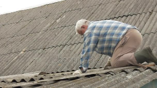 Un anciano está arreglando el techo él mismo. Antigua casa de madera en pizarra — Vídeos de Stock