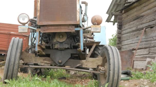 Ein alter rostiger Traktor steht neben dem Feld. die Maschine für die Landwirtschaft wartet auf die Verarbeitung des Feldes — Stockvideo