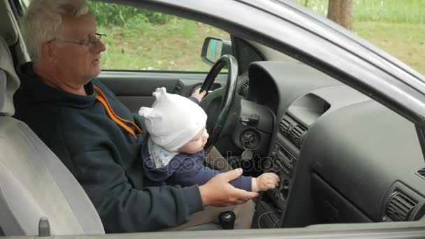 Der Großvater spielt während der Fahrt mit dem Jungen im Auto. Der Enkel ist sehr glücklich und dreht die verschiedenen Knöpfe — Stockvideo