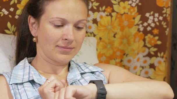 Fiatal nő ellenőrzi az üzeneteket a smartwatch otthon a kanapén. — Stock videók