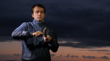 Adam ahşap-yün yangın günbatımında sahada başlatmak için av bıçağı ile hazırlar. Ahşap tıraş. Hayatta kalma kavramı