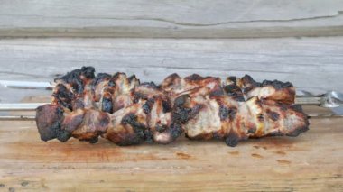 Bir Barbekü içinde pişmiş et bir ahşap tahta üzerine yerleştirilir. Kırmızı, biraz yanmış parçalar. Arka planda ahşap duvar