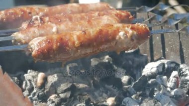 Yağlı iştah açıcı sosis ateşte pişirin. Ateşe yağ drips. Bir sürü duman kömürlerin.