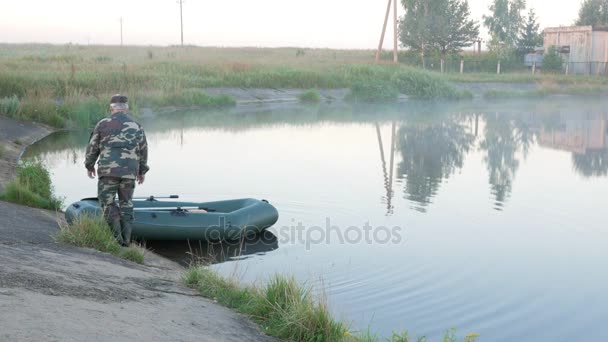 Opblaasbare boot met een mannelijke visser op een meertje in de mist. Vroeg in de ochtend. — Stockvideo