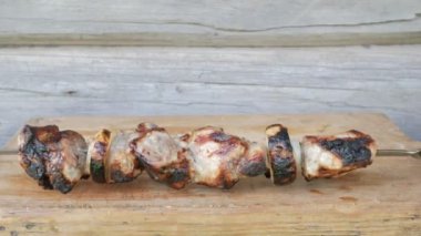Bir Barbekü içinde pişmiş et bir ahşap tahta üzerine yerleştirilir. Kırmızı, biraz yanmış parçalar. Arka planda ahşap duvar
