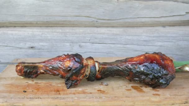 Viande cuite dans un barbecue sur une planche de bois aux oignons verts. Ruddy, des morceaux légèrement brûlés. Mur en bois sur le fond — Video