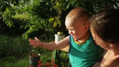 Anne ve bebek çocuk evin verandada yağmur damlaları tadını çıkarın. Çok su ile mutlu ve gün batımında kısma oğludur