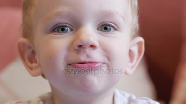 Söt rolig pojke drar sina läppar och skrattar. Heminredning i bakgrunden. Närbild — Stockvideo