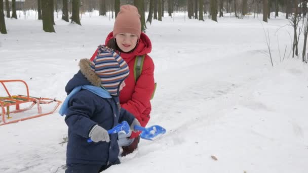 かわいい小さな少年や青年母遊び冬の公園で雪に。青い子供ジャケットと赤のお母さん. — ストック動画