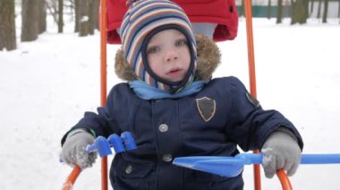 Sevimli küçük çocuk ve genç anne kış ile oyun kar parkta. Mavi çocuk ceket ve anne, kırmızı.