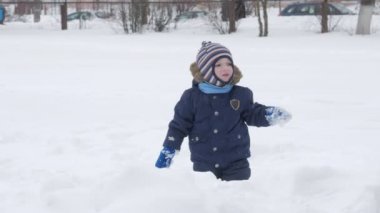 Sevimli küçük çocuk ve genç anne kış ile oyun kar parkta. Mavi çocuk ceket ve anne, kırmızı.