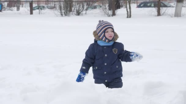 Schattige kleine jongen en jonge moeder spelen in de winter met sneeuw in het park. Blauwe kids jas en rood aan moeder. — Stockvideo