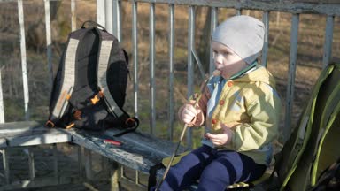 Güzel bir çocuk bir sosis dışarıda yiyor. Yangın Barbekü üzerinde pişmiş