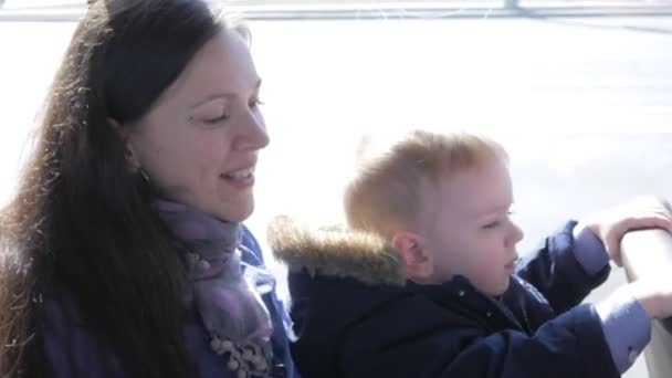 Молодая мать и мальчик едут на автобусе. Улыбнись и посмотри в камеру. — стоковое видео