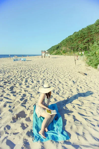 Retrato de uma jovem morena relaxando na praia, lendo um bo — Fotografia de Stock