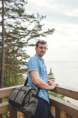 park ve gülümseyen ahşap merdivenlerde oturan adam