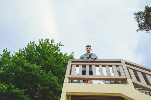 Man sitting on the wooden stairs in park and smiling — Stock Photo, Image
