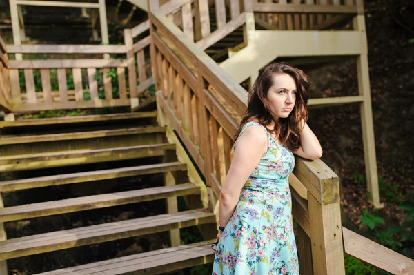 Девушка сидит на деревянной лестнице в парке и улыбается — стоковое фото