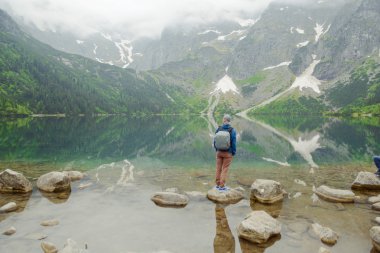 Adam gölde ve dağlarda dinleniyor. Güneşli manzara.