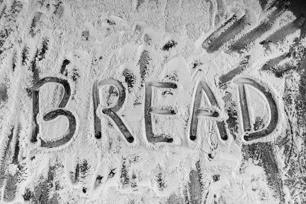 Palabra de pan escrita en harina en la mesa — Foto de Stock
