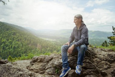 Erkek dinlenme ve kayanın üzerinde oturan dağ zevk