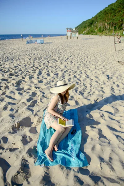 Ritratto di una giovane bruna che si rilassa sulla spiaggia, leggendo un libro — Foto Stock