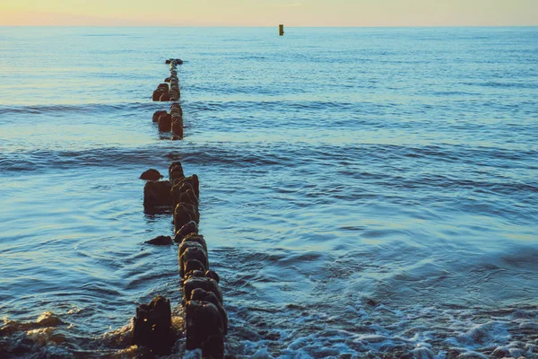 Rompeolas en el mar Báltico sobre el atardecer — Foto de Stock