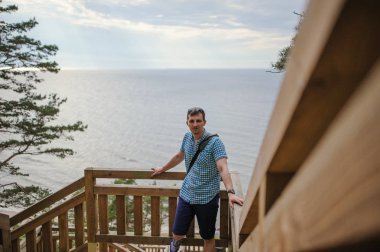 park ve gülümseyen ahşap merdivenlerde oturan adam