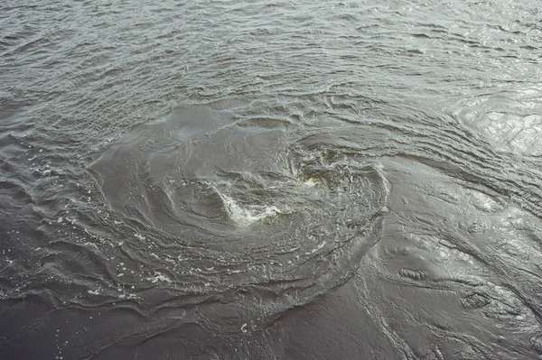 A blue water vortex that funnels below the surface