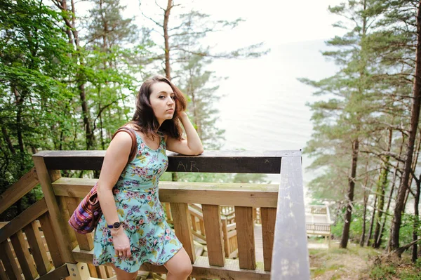 Flickan sitter i trä trappan i park och leende — Stockfoto