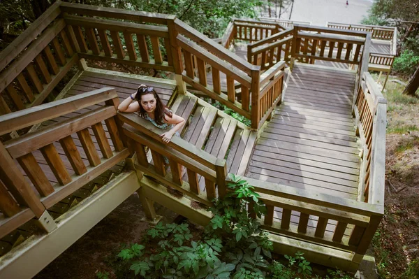 Menina sentada nas escadas de madeira no parque e sorrindo — Fotografia de Stock