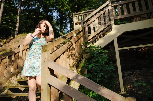 Park ve gülümseyen ahşap merdivenlerde oturan kız — Stok fotoğraf
